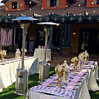 Patio heaters beside long tables set for an outdoor dinner