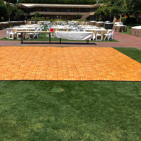 Wood dance floor set on a lawn with tables beyond