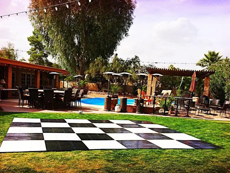 Black and white checkered dance floor set on a lawn with desert mountains behind