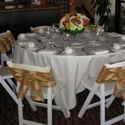 Round table with a white tablecloth and gold chair sashes